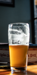 Glass of beer with foam on a wooden surface, with a blurred background